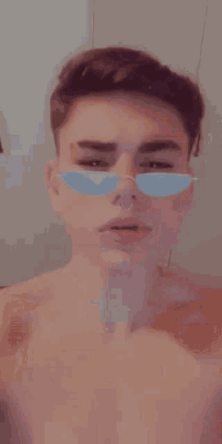 a shirtless young man wearing sunglasses and a nose ring .