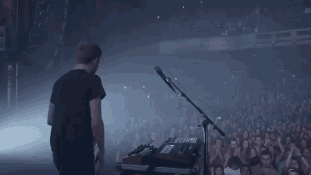 a man is playing a keyboard on stage in front of a crowd .