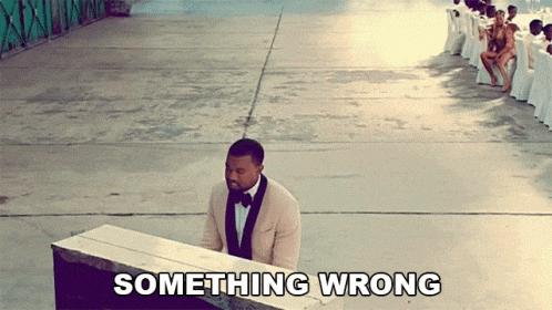 a man in a tuxedo is playing a piano with something wrong written on the ground behind him