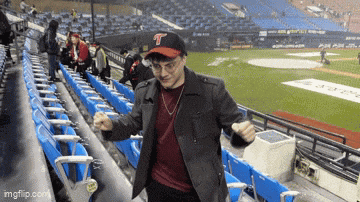 a man wearing a baseball cap with the letter t on it stands in a stadium