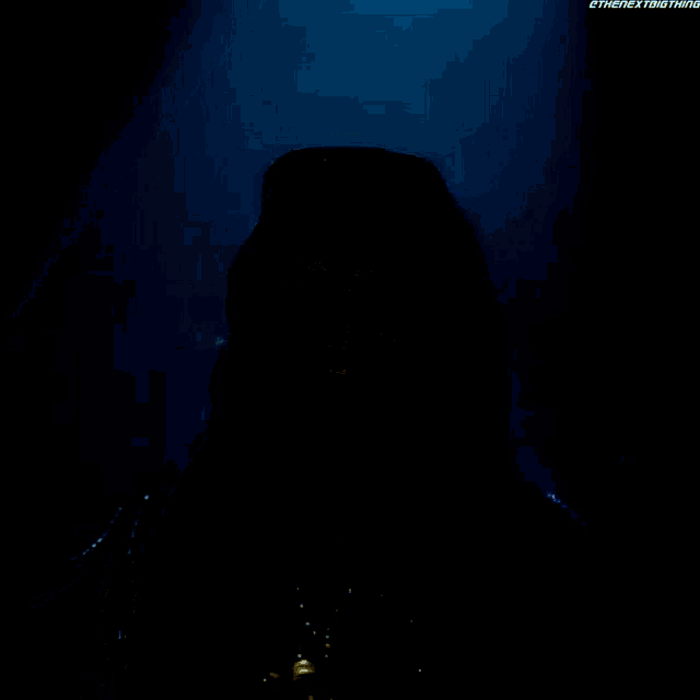 a woman with blue hair and sunglasses stands in a dark room .