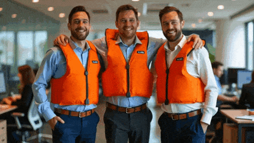 three men are posing for a picture with one wearing a life vest