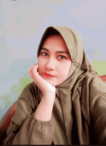 a woman wearing a hijab has her hand on her face