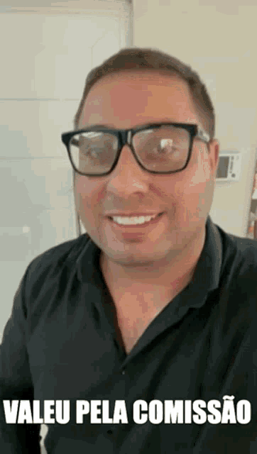 a man wearing glasses and a black shirt is smiling with the words valeu pela comissao below him