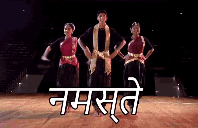 three people are dancing in front of a sign that says ' namaste '