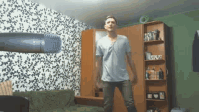 a man is standing in front of a microphone in a room with a love sign on the shelf