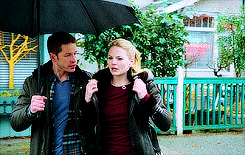 a man and a woman are holding an umbrella in the rain .