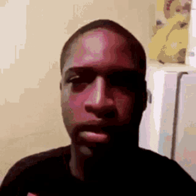 a young man is taking a selfie in front of a refrigerator in a kitchen .