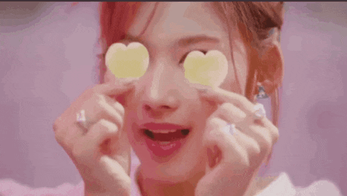 a woman with pink hair is holding a heart shaped candy in her hand
