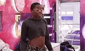 a woman in a crop top and shorts is standing in a room .
