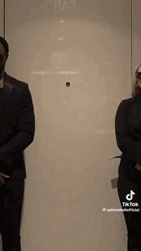 a man in a suit and a woman in a dress are standing next to each other in a doorway .