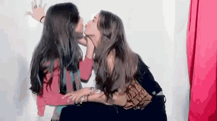 two women are kissing in a photo booth .
