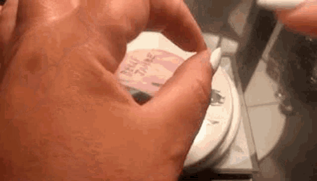 a close up of a person 's hand holding a cd on a table .
