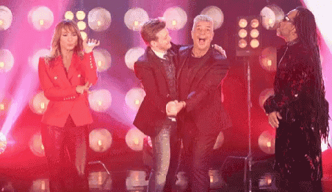 a group of people are standing on a stage with a woman in a red jacket .