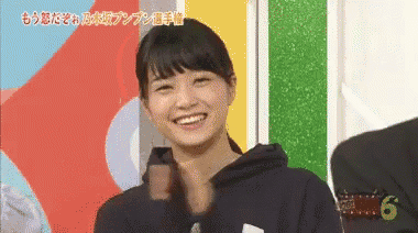 a woman in a black hoodie is smiling and looking at the camera .