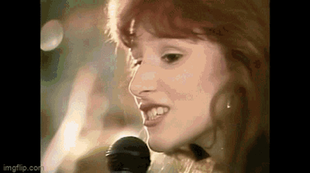 a woman is singing into a microphone in a close up .