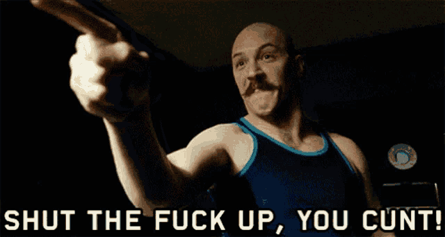 a man with a mustache is pointing at someone and the words shut the fuck up you cunt