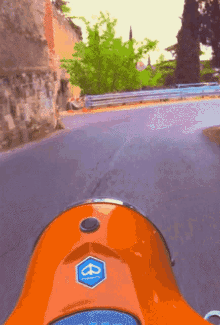 an orange vespa scooter is driving down a street