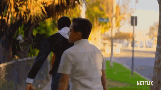 two men walking down a sidewalk with a netflix logo on the bottom