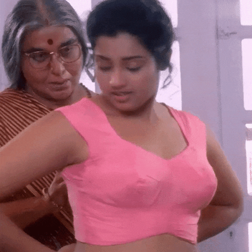 a woman in a pink crop top is being helped by a woman in glasses .