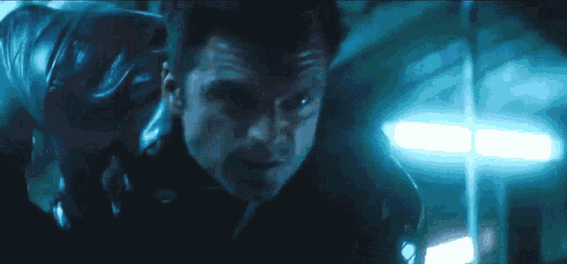 a close up of a man 's face in a dark room with blue lights
