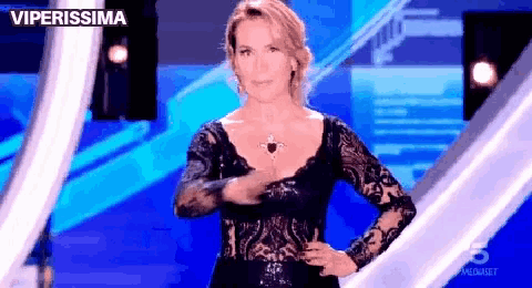 a woman in a black lace dress is standing on a stage with her hands on her hips and the words viperissima above her
