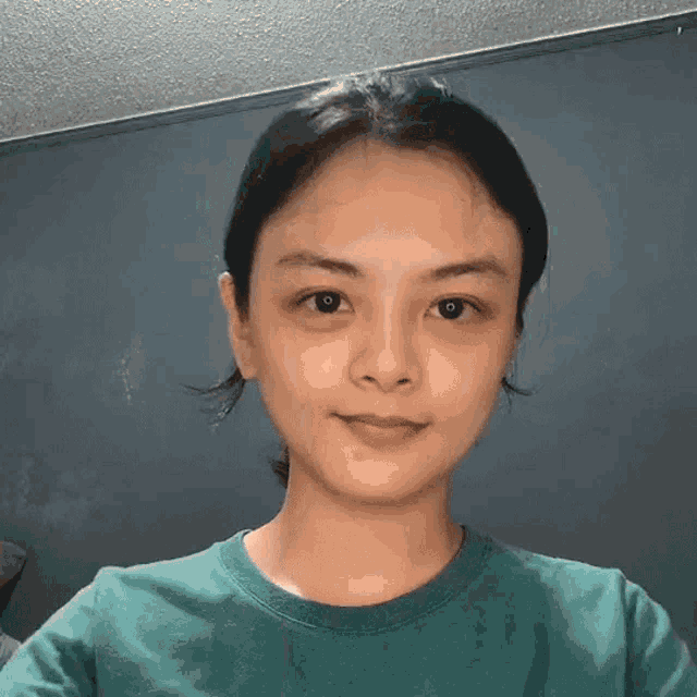 a young woman wearing a green shirt is smiling for the camera