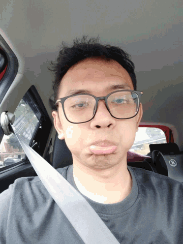 a man wearing glasses and a seat belt is making a face