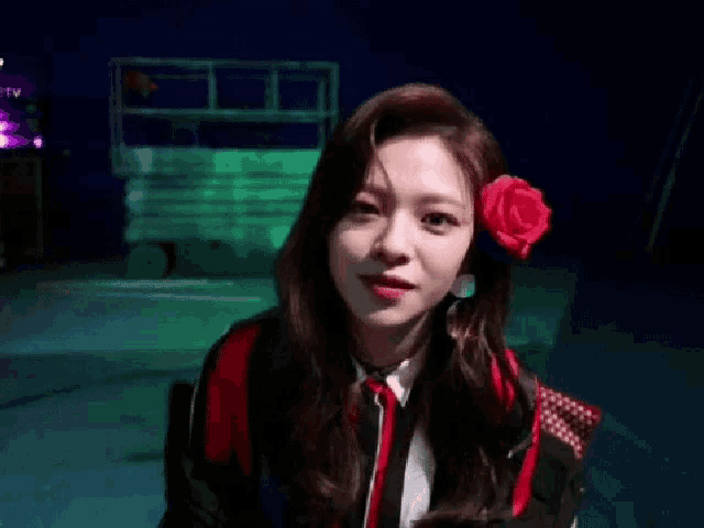 a woman with a red rose in her hair is smiling and giving a fist bump .