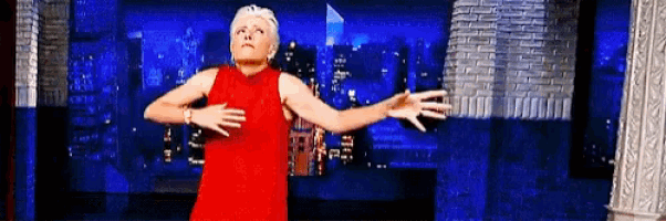 a woman in a red dress is dancing in front of a blue background .