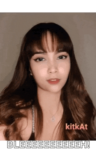 a woman with long hair and bangs is wearing a necklace and a black top .