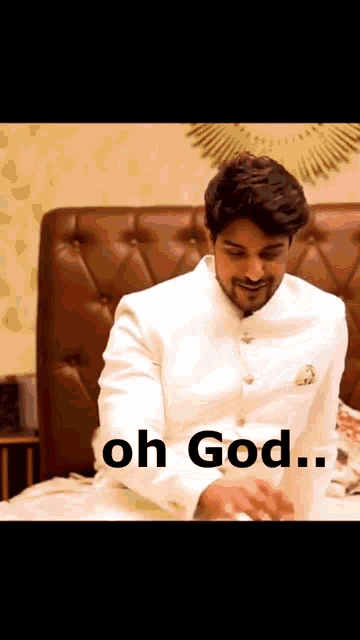 a man in a white suit is sitting on a bed with the words oh god written below him .