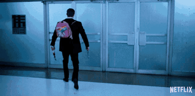 a man with a pink backpack is walking down a hallway with netflix on the bottom