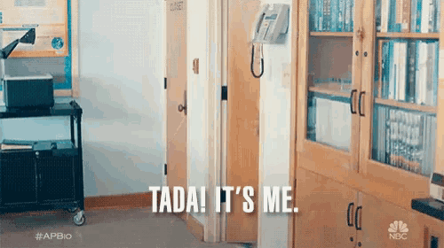a person is standing in a hallway with a phone hanging on the wall and says " tata it 's me "