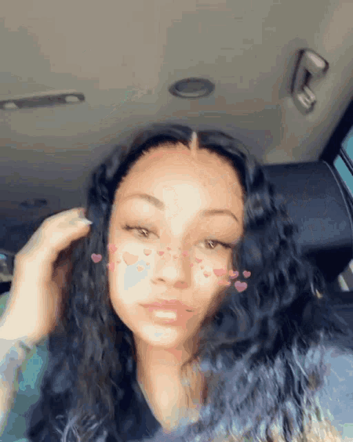 a girl with hearts on her face is sitting in the back seat of a car .