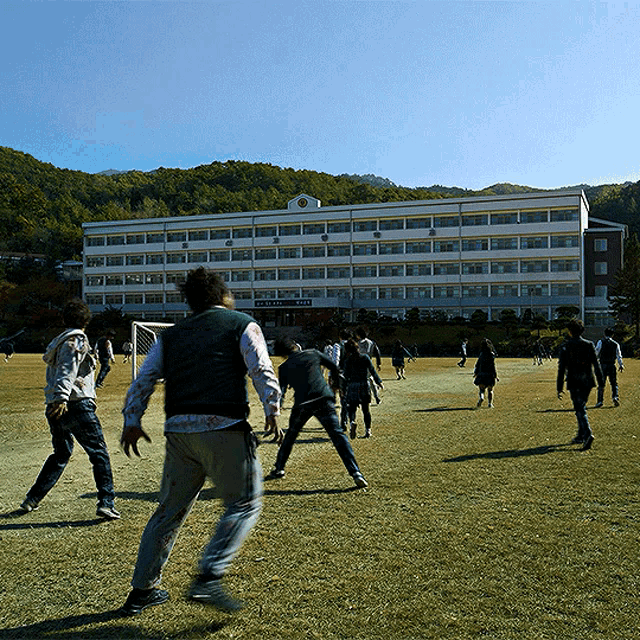 a group of people playing soccer in front of a building that says university