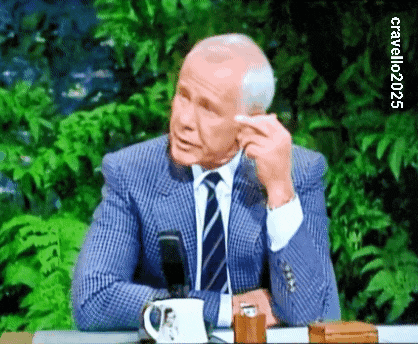 a man in a suit and tie is sitting at a table with a cup of coffee in front of him