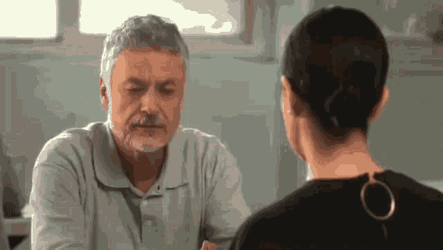 a man and a woman are sitting at a table and talking