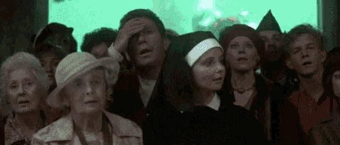 a group of people are standing in front of a green screen and looking at something .