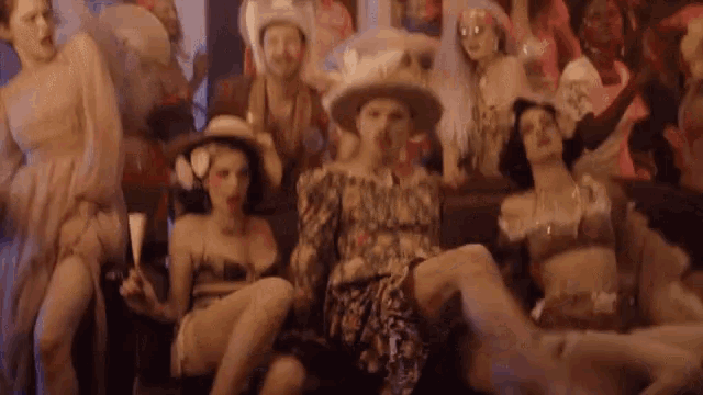 a group of women are sitting on a couch with a man standing behind them .