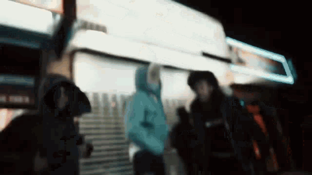 a blurry picture of a group of people standing outside of a building at night .