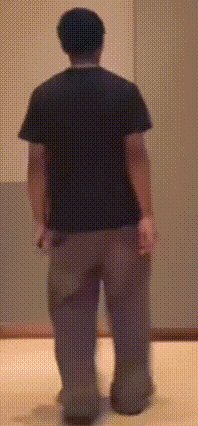 a man in a black shirt and brown pants stands in front of a wall