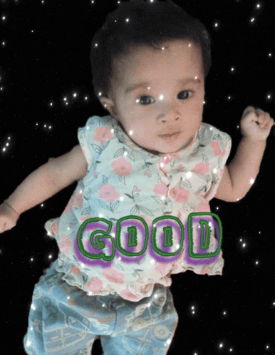 a baby girl with the word good written on her shirt