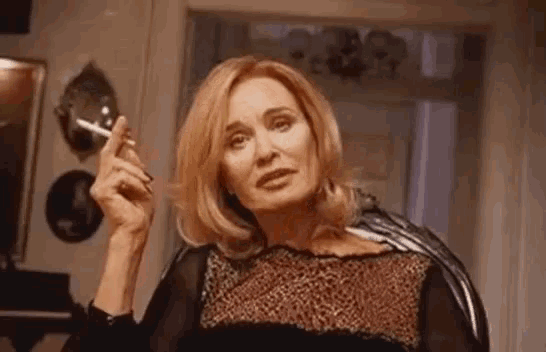a woman is smoking a cigarette in a living room while wearing a leopard print dress .