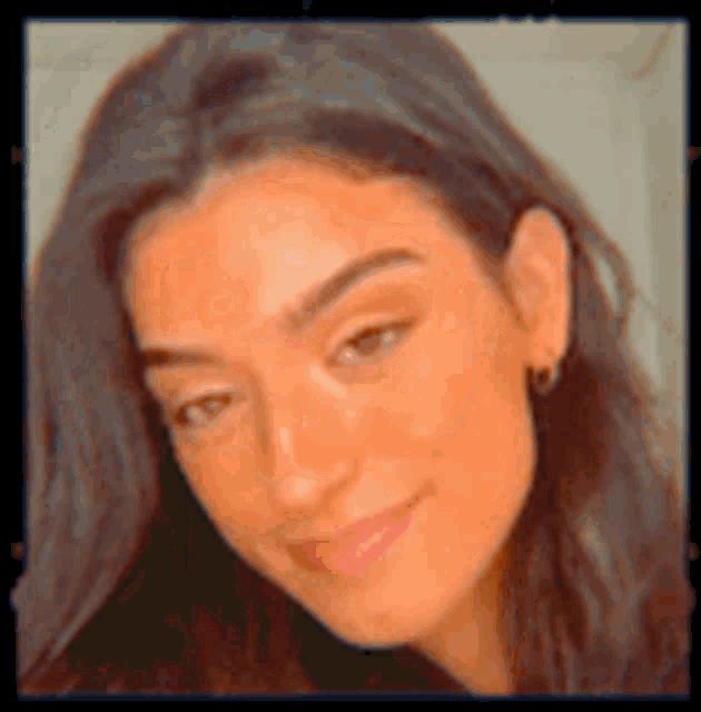 a close up of a woman 's face with long dark hair and earrings .