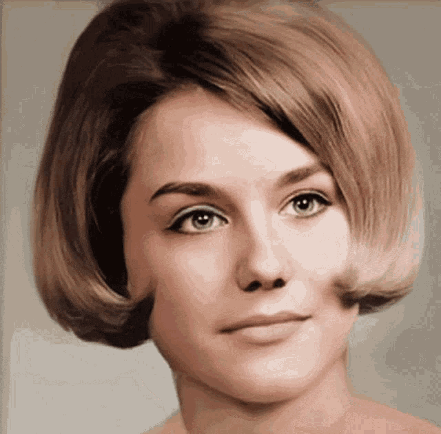 a woman with short blonde hair and green eyes looks at the camera