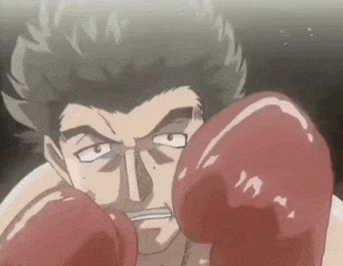 a man wearing red boxing gloves is looking at the camera in a boxing ring .