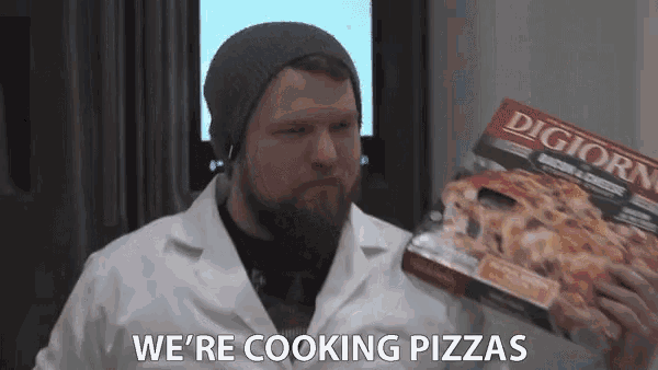 a man in a lab coat is holding a box of pizza and saying we 're cooking pizzas
