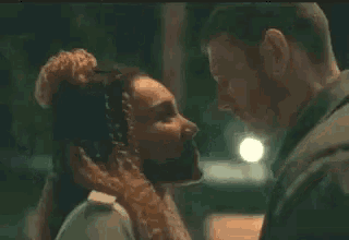 a man and a woman are kissing in front of a street light at night .