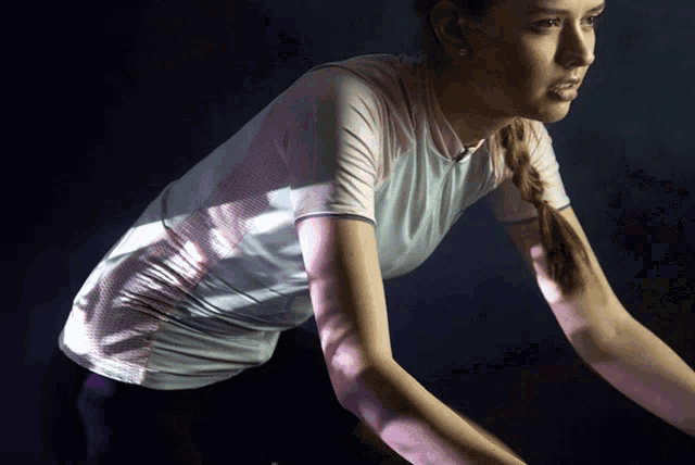 a woman wearing a white shirt and purple pants is standing in a dark room